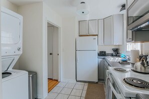A compact kitchen with white appliances, a stove, and cabinets.
