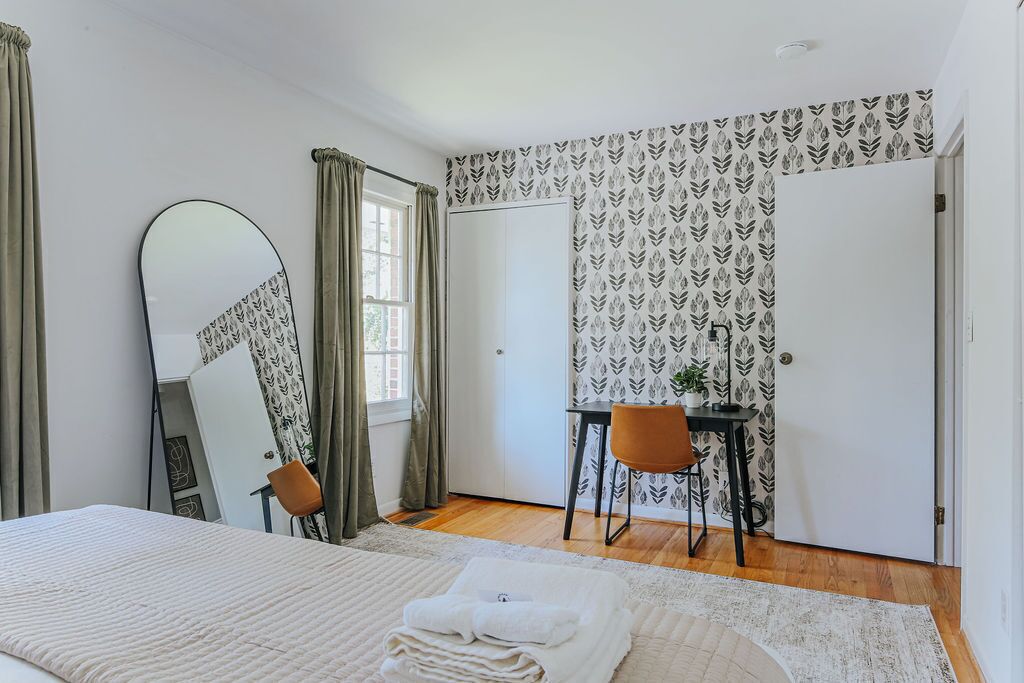 Un dormitorio con cama, escritorio, silla, espejo y armario.
