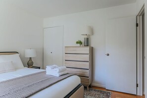 A neatly arranged bedroom with a bed, bedside tables, a wardrobe, and a door.