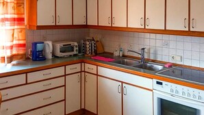 Eine Küche mit weißen Schränken, einem Spülbecken, einem Bosch-Ofen, einem Toaster und einem Wasserkocher.