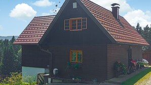 Ein zweistöckiges Haus mit steilem Dach, einem kleinen Dachfenster und einem Schornstein.