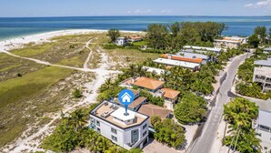Ein Küsteneigentum mit Blick auf den Strand, mehreren Gebäuden und einem auffälligen Haus mit blauem Symbol.