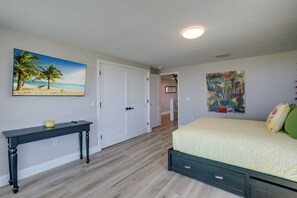 A bedroom with a bed, a desk, and two paintings.
