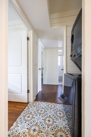 A hallway with a patterned tile floor, white doors, and a black appliance.