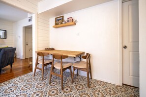 Ein Essbereich mit Holztisch, vier Stühlen, einer Regal mit Dekoration und einem gemusterten Boden.