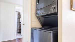 A compact kitchen with a built-in oven and microwave, a patterned tile floor, and a door leading to another room. - Vintage Rosedale Bungalow in Rosedale (Austin)