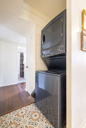 A compact kitchen with a built-in oven and microwave, a patterned tile floor, and a door leading to another room.