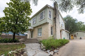 A two-story house with a stone facade, a front porch, and a small attached garage.