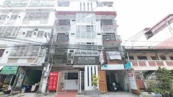 A multi-story building with a central entrance, balconies, and various storefronts on the ground level.