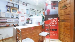 A hotel reception area with a wooden counter, framed certificates on the wall, and a promotional poster for a loyalty program. - RedDoorz @ DBuilders Rooms Ph1 Taguig (Taguig)