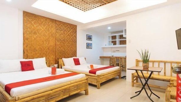 A room with two beds, a small table, and a bench. - RedDoorz @ DBuilders Rooms Ph1 Taguig (Taguig)