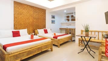 A hotel room with two beds, a small table, and a bench.