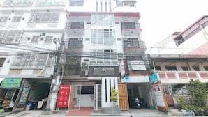 A multi-story building with a central entrance, surrounded by various shops and businesses. - RedDoorz @ DBuilders Rooms Ph1 Taguig (Taguig)