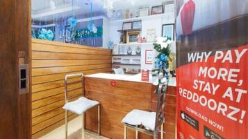A reception area with a wooden counter, two chairs, and a poster advertising a service.