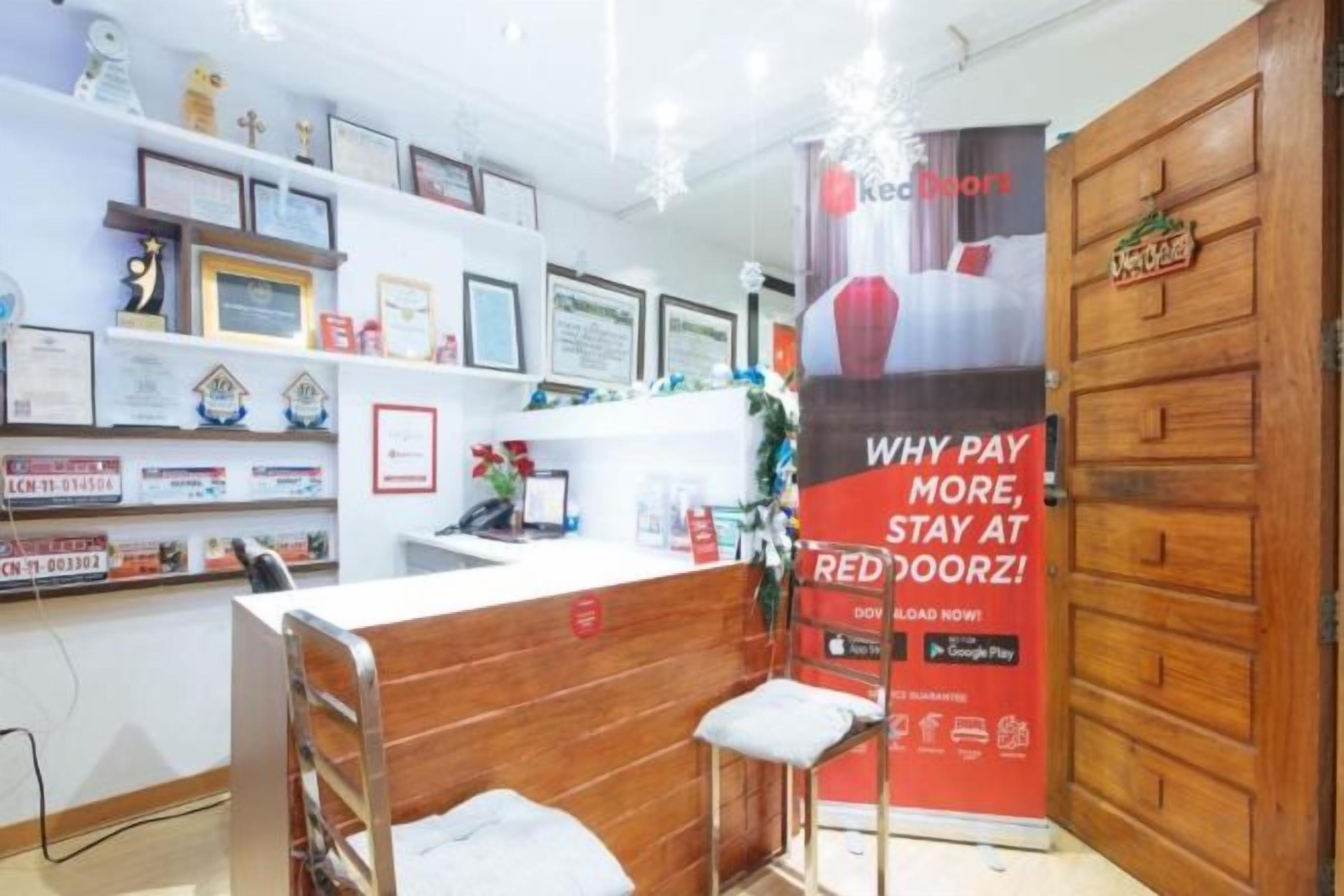 A hotel reception area with a wooden counter, framed certificates on the wall, and a large red sign advertising a special offer.