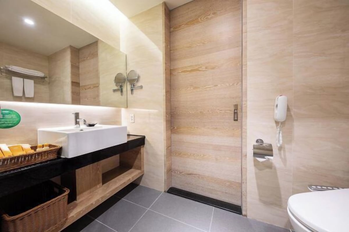 A modern bathroom with a white sink, a mirror, a shower area, and a toilet.