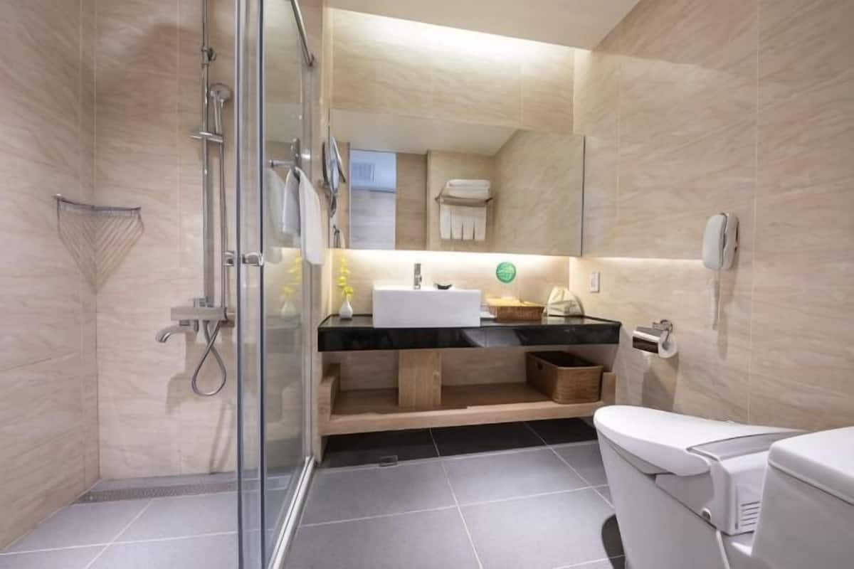 Ein modernes Badezimmer mit Duschkabine aus Glas, Waschbecken mit Spiegel und Toilette.