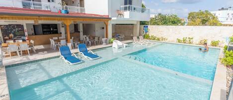 A swimming pool with lounge chairs and a bar area.