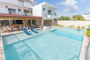 Una piscina con sillas de descanso y zona de bar.