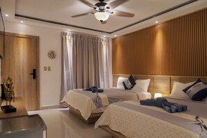 A hotel room with two beds, a ceiling fan, a wooden panel wall, and a large window with curtains. - Casual On the Beach Bayahibe by Casual Hoteles (Bayahíbe)