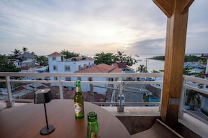 A balcony with a table, two bottles, and a view of a coastal town with buildings and boats. - Casual On the Beach Bayahibe by Casual Hoteles (Bayahíbe)
