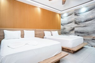 Habitación de hotel con dos camas, cabeceros de madera y una pared de mármol.