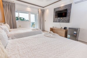 A hotel room with two beds, a TV mounted on the wall, a minibar, and a view of the outdoors. - Casual On the Beach Bayahibe by Casual Hoteles (Bayahíbe)