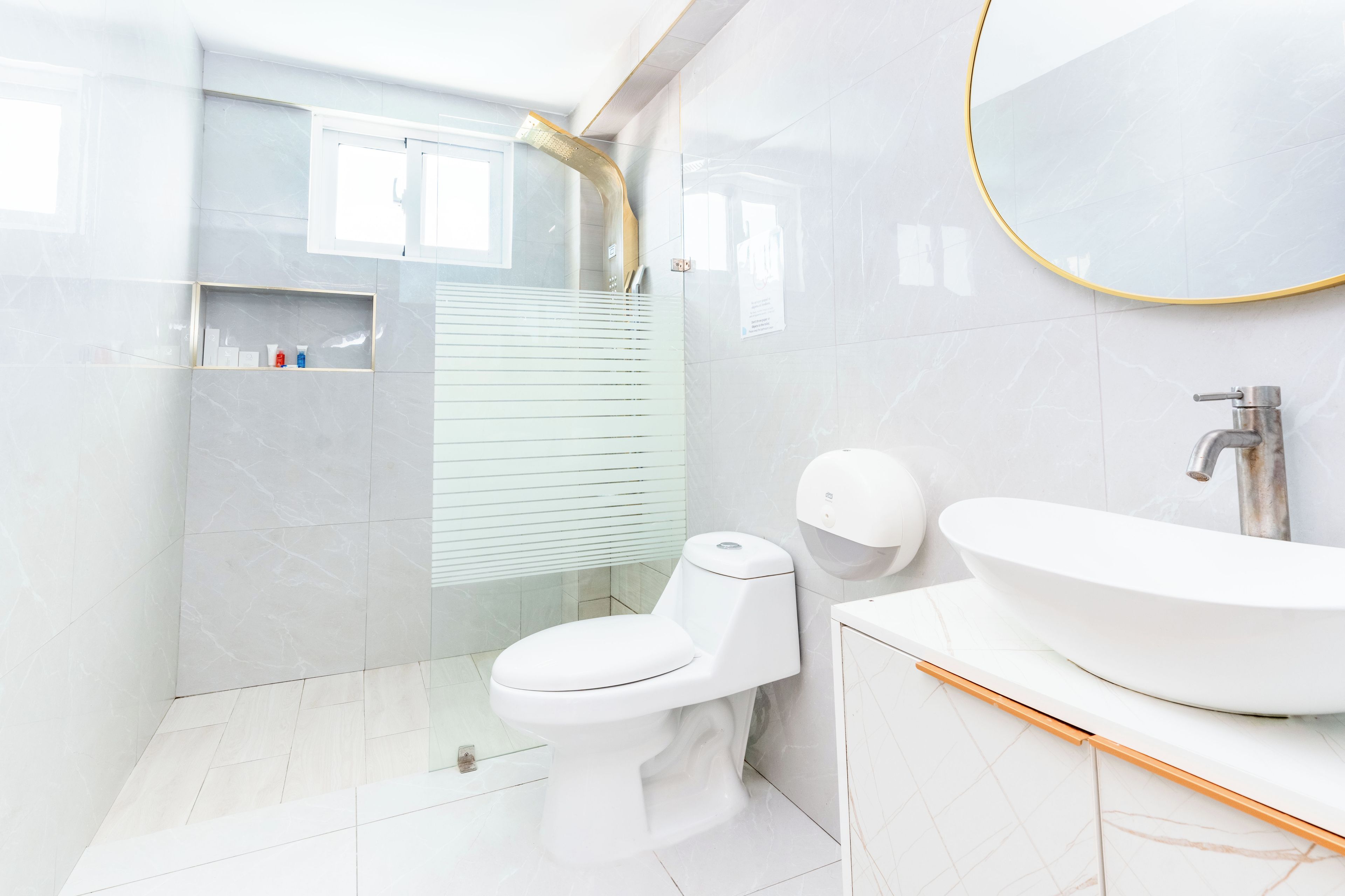 A modern bathroom with a white sink, a toilet, and a shower area.