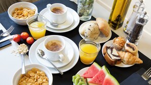 Desayuno con cereal, café, jugo, croissants y rebanadas de sandía.