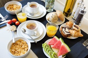 A breakfast setting with cereal, coffee, juice, croissants, and watermelon slices. - Casual On the Beach Bayahibe by Casual Hoteles (Bayahíbe)
