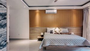 A modern bedroom with a wooden headboard, a bed with a quilted cover, and a nightstand with a lamp. - Soficu Hotel On The Beach (Bayahíbe)