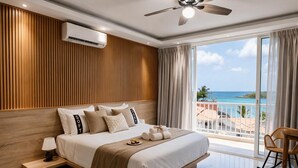 A modern bedroom with a large bed, a ceiling fan, an air conditioning unit, and a balcony with a view of the ocean. - Casual On the Beach Bayahibe by Casual Hoteles (Bayahíbe)