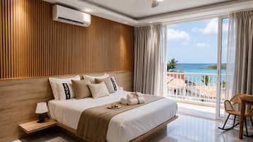 Un dormitorio moderno con una cama grande, un ventilador de techo, un equipo de aire acondicionado y un balcón con vista al océano.