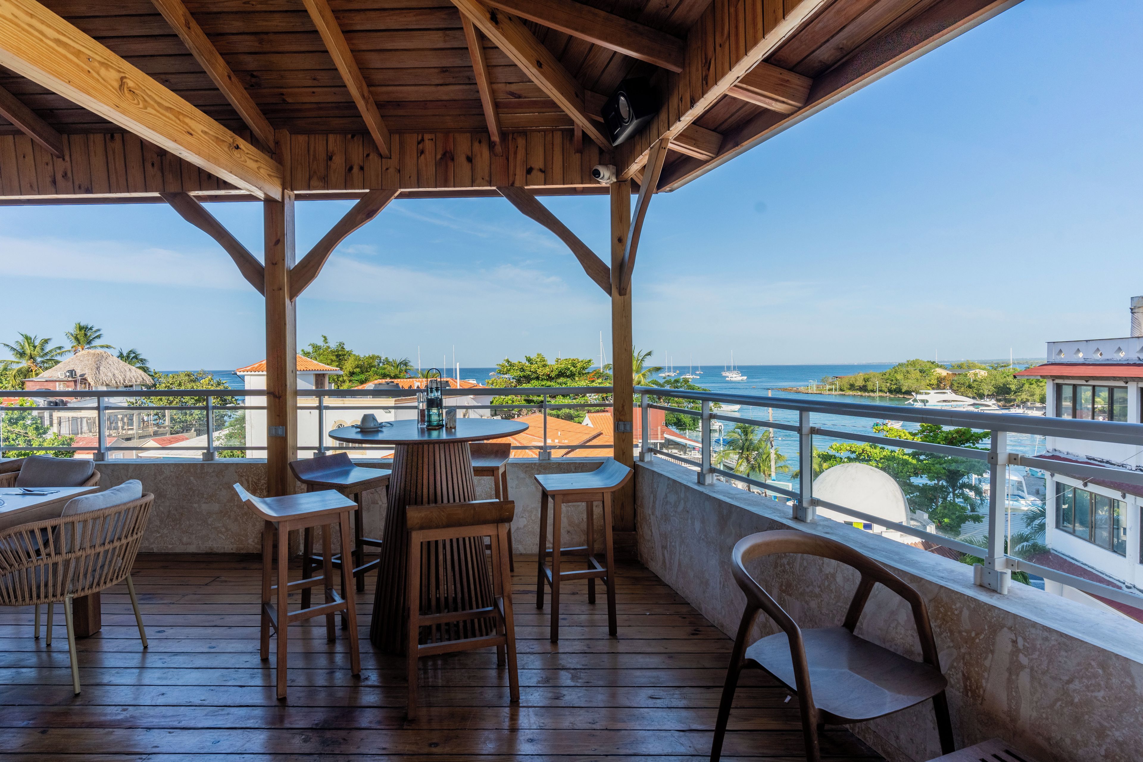 A wooden deck with outdoor seating, overlooking a marina and the sea.