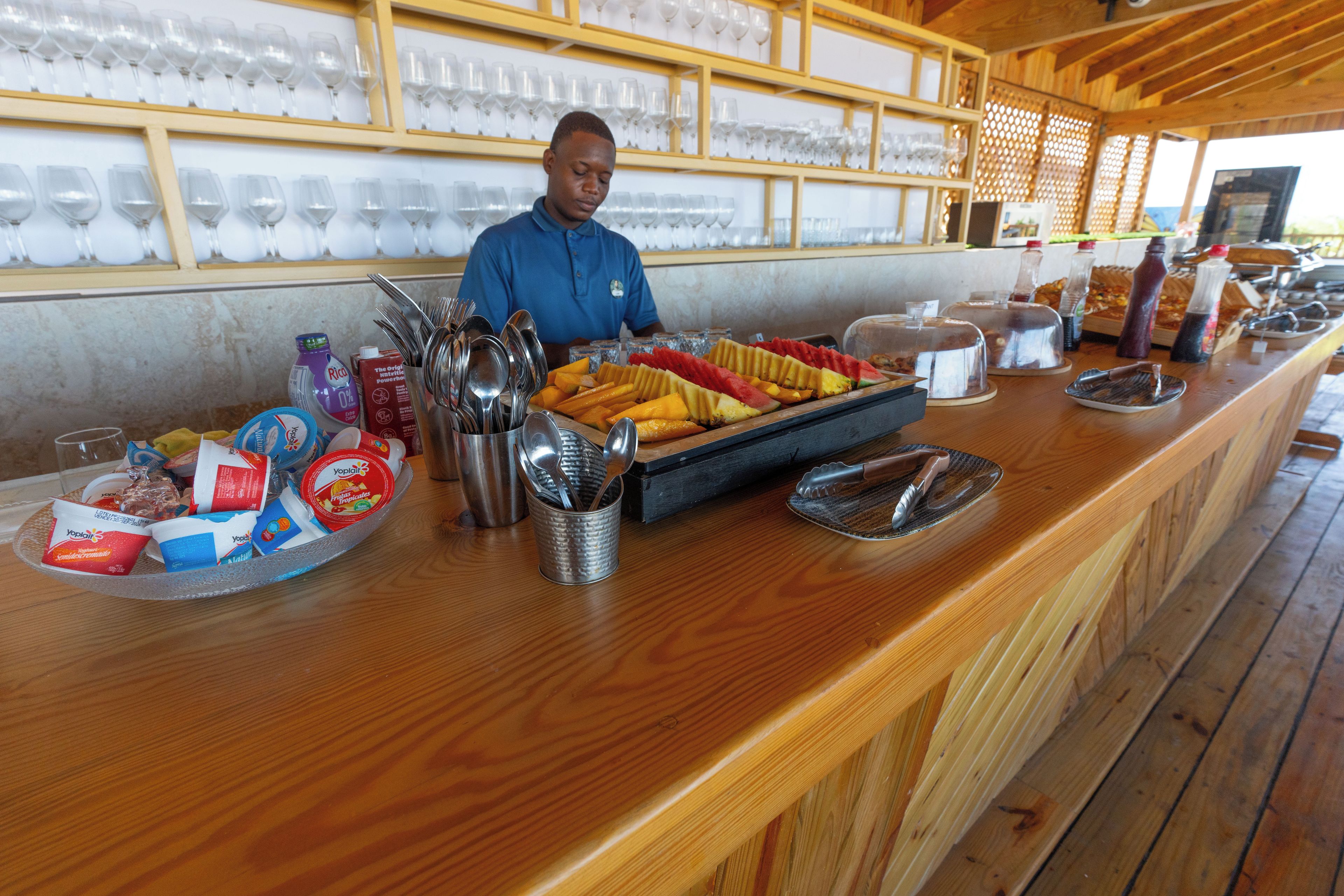 Ein Buffet mit verschiedenen Speisen, Geschirr und einer Person, die etwas ausgibt.