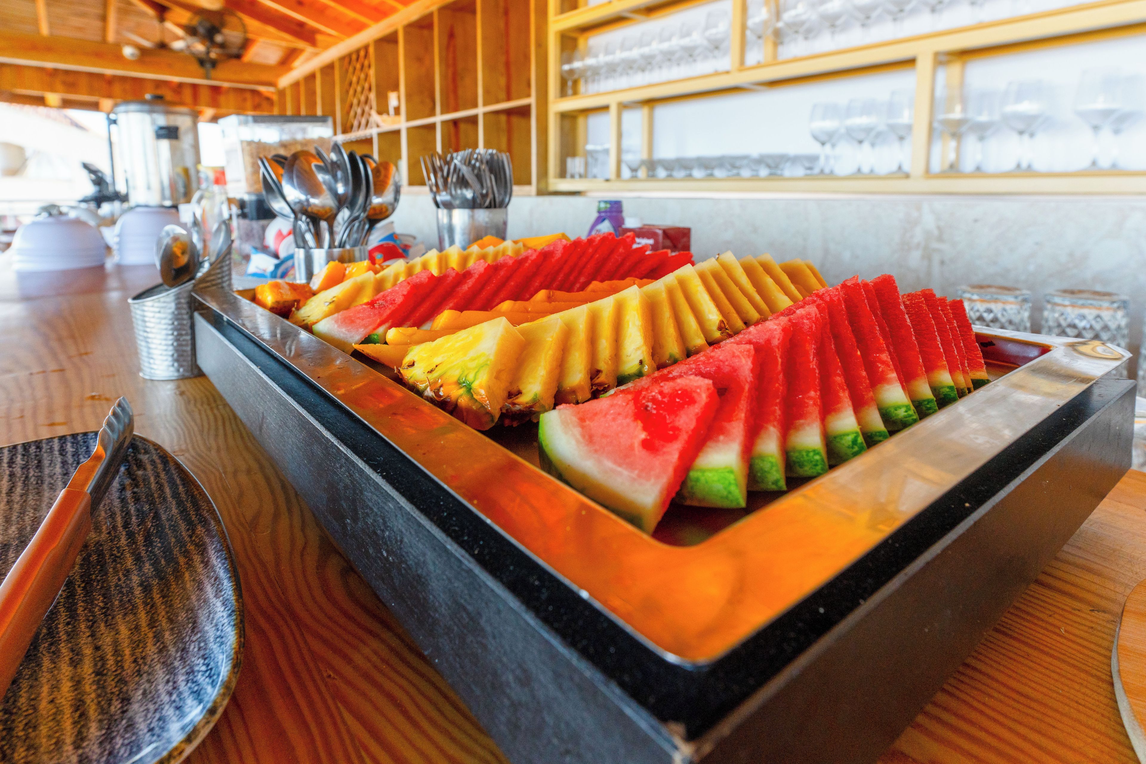 A buffet with a variety of sliced fruits arranged in a tray.
