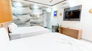 Un dormitorio moderno con una cama grande, un televisor de pantalla plana montado en la pared y un ventilador de techo.