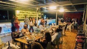 A rooftop bar with outdoor seating, a pool, and a bar area with illuminated shelves. - Soficu Hotel On The Beach (Bayahíbe)