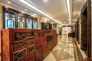 Un vestíbulo de hotel con mostrador de recepción, una araña y un mostrador de registro.