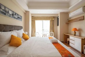 Camera d'albergo con un letto grande, una scrivania, una sedia e una finestra con tende.