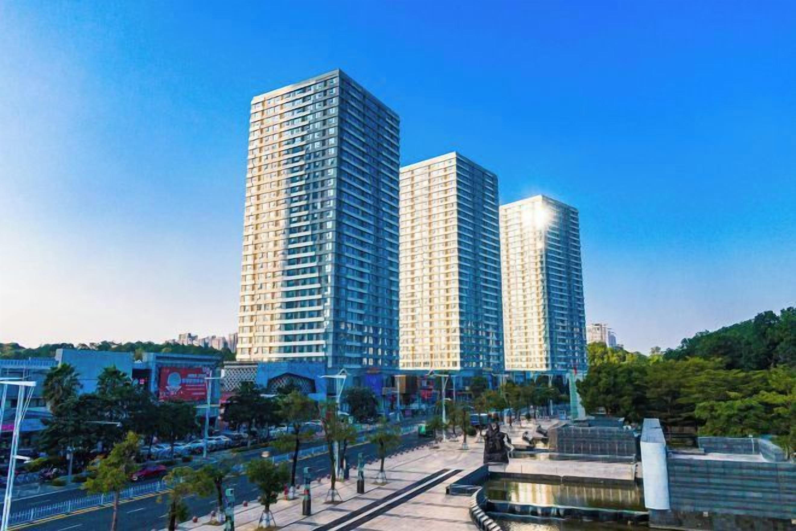 Un immeuble moderne de grande hauteur, doté d’une façade en verre, situé dans un environnement urbain sous un ciel dégagé.