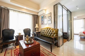 Habitación de hotel con sofá, sillas, un armario de madera y una partición de vidrio.