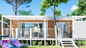 A two-story wooden cabin with a balcony, a covered patio area, and a small deck. - Cosy apartment in villa for 4 guests with WIFI, A/C, pool and terrace (Castiglione Della Pescaia)
