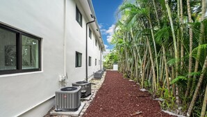 Een pad dat leidt naar een gebouw met airconditioners en een rij palmbomen.