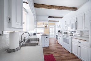 Uma cozinha moderna com armários brancos, eletrodomésticos de aço inoxidável e um vigamento de madeira.