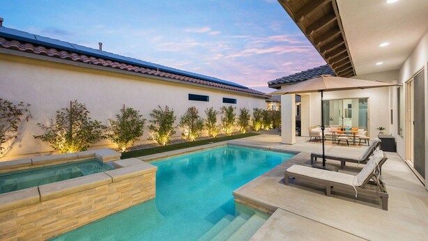 A swimming pool with a sunken area, surrounded by a patio with lounge chairs and a table, and a covered seating area with a table and chairs. - Play Paradise: Pool+Spa, BBQ, GameRoom, PGA West! (La Quinta)