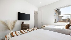 A bedroom with two beds, a television, a window, and a door. - Play Paradise: Pool+Spa, BBQ, GameRoom, PGA West! (La Quinta)
