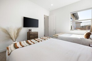 A bedroom with two beds, a television, a window, and a door. - Play Paradise: Pool+Spa, BBQ, GameRoom, PGA West! (La Quinta)