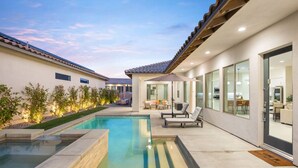 A modern outdoor pool area with a patio, seating, and a view of the adjacent building. - Play Paradise: Pool+Spa, BBQ, GameRoom, PGA West! (La Quinta)