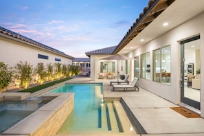 A modern outdoor pool area with a patio, seating, and a view of the adjacent building. - Play Paradise: Pool+Spa, BBQ, GameRoom, PGA West! (La Quinta)